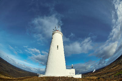 White Reykjanesviti lighthouse viewed from below against a blue sky on the Reykjanes Peninsula, Iceland.