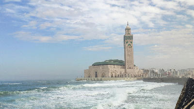 Hassan II Mosque rises above the Atlantic Ocean in Casablanca, with waves breaking along Morocco’s urban Atlantic coastline.