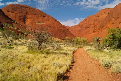 Walking trail through spinifex grass beneath the red sandstone domes of Kata Tjuta, Northern Territory, Australia.