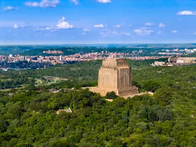 Aerial view of the Voortrekker Monument overlooking Pretoria with the city skyline and Union Buildings in the background.